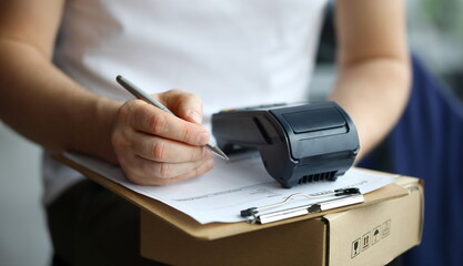 Man fills in home delivery mail document on box. Banking application. POS-terminal provides...