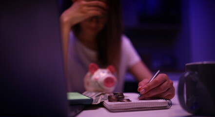 Upset woman leaned over family budget and money. Revision family budget after job loss. Tension in...