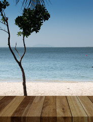 wood table top on Tranquil beachscape featuring a lone tree, clear blue skies, and serene waters – a picturesque vacation spot blending nature's beauty. in thailand.