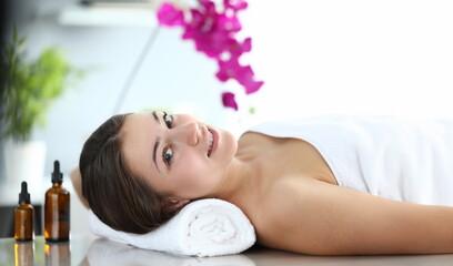 Obraz na płótnie Canvas Happy girl is lying in massage room and smiling. Improve health and well-being. Muscle tension after heavy physical exertion or hard day. Maintain vitality body and strengthen immune system
