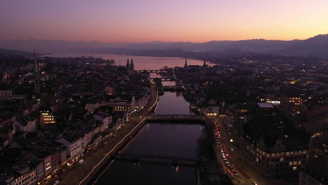 Zurich, Switzerland: Cinematic aerial drone footage along the Limmat river in Zurich old town and the modern business district at sunset in Switzerland largest city. Shot with a tilt up motion