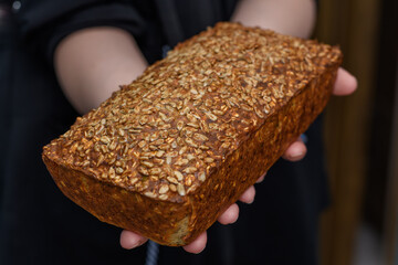 Świeży pieczony chrupiący chleb z ziarnami słonecznika trzymany w dłoniach 