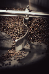 Close up of beans in a stainless steel industrial coffee roaster for an artisan coffee maker.