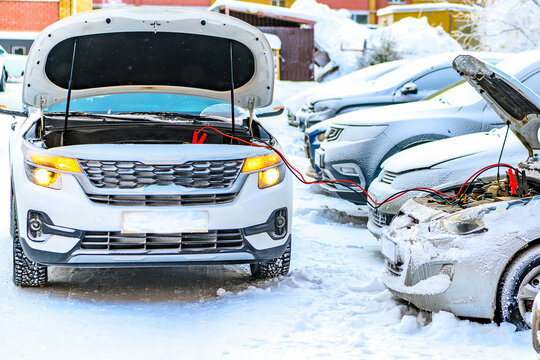 Charging automobile discharged battery by booster jumper cables at winter.  Problem starting a car in extreme freezing conditions.Technical assistance on roads in winter, hazard warning light.