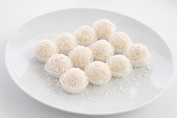 Candies with coconut flakes on the plate. Selective focus.White background.