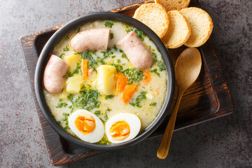 Zurek Traditional Polish soup on rye sourdough with sausage and egg close-up in a bowl on the...