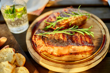 A succulent ribeye steak, perfectly grilled and adorned with fresh rosemary sprigs, rests on a circular wooden plate against a dark, rustic backdrop.