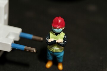 miniature figurine of an electrician with an electric plug