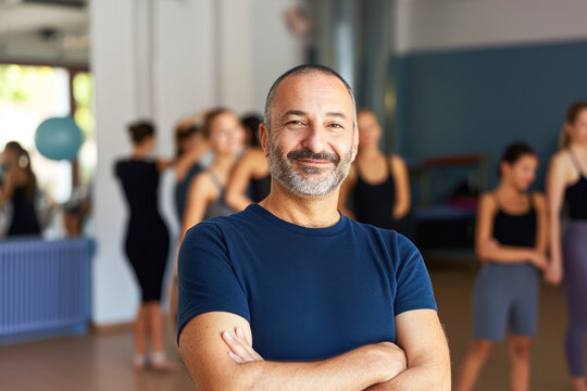 Portrait of smiling senior man standing with arms crossed in fitness studio