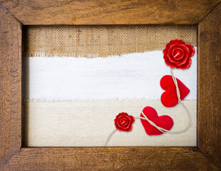Two red hearts and rose candle flower in wooden frame with space on canvas fabric background, love...