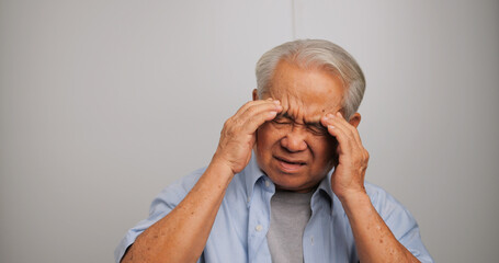 Asian old man with migraine headache. Elderly man suffering from a headache.
