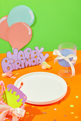 A white ceramic plate is displayed on an orange background. Cute shapes are cut from colored paper and decorated with confetti. Free space for display.