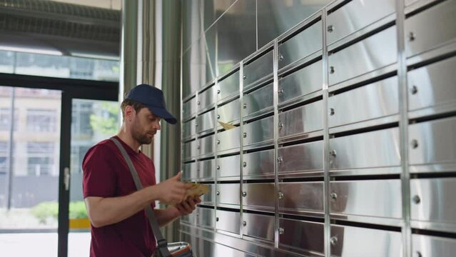 Mailman putting post correspondence into lockers. Closeup silver post containers