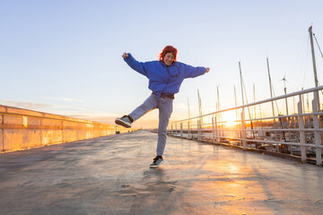 woman dancing in a port at sunset, red hair, smiling