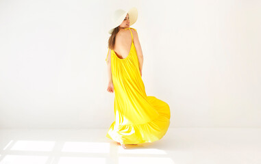 Young happy beautiful romantic woman in long yellow summer dress and wicker hat isolated on white