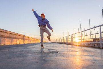 Fototapeta na wymiar woman dancing in a port at sunset, red hair, smiling