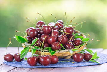 Sweet Red cherry in bamboo basket on green bokeh background, Red cherry on blurred greenery background.