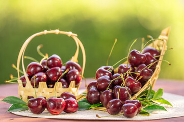 Sweet Red cherry in bamboo basket on green bokeh background, Red cherry on blurred greenery background.