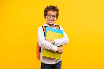 Nerdy boy with glasses holding books, orange backpack