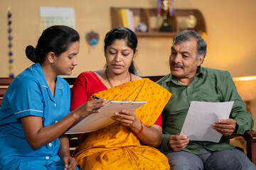 Nurse or caregiver guiding or taking signature from senior patents by reviewing medical paper documents at home - concept of professional occupation, healthcare service and agreement