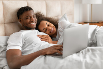 Loving african american couple having cozy morning cuddling in bed