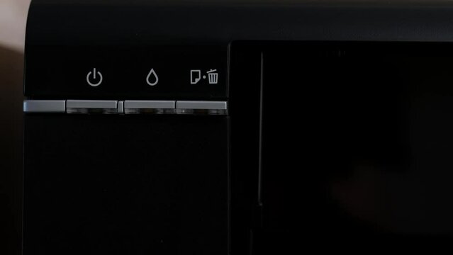 Turning on the printer. Green power light on the black printer body, close-up. Office Equipment.Multifunction device. Multifunction printer.
