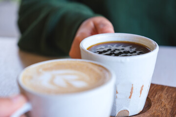 Closeup image of a couple people holding and clinking coffee cups together in cafe