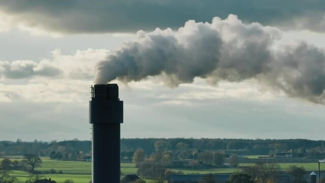 Smoking factory chimney in open landscape