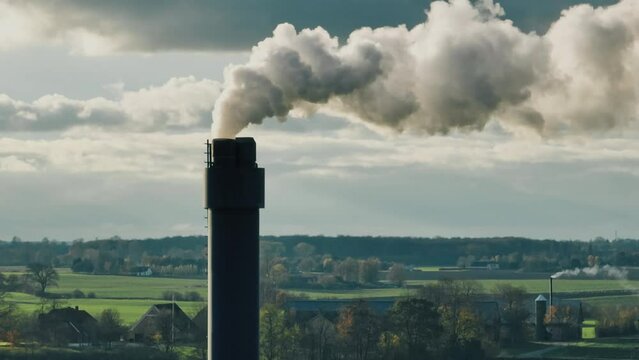 Smoking factory chimney in open landscape