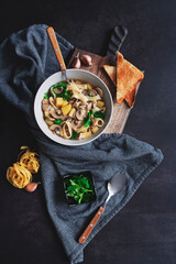 vegetarian noodle mushroom soup with potato served with toast on dark rustic background