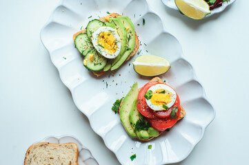 healthy vegetarian breakfast, avocado toast with cucumber, eggs, tomato and greean salad on wholegrain bread