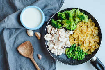 ingredients for cooking tasty one pot italian pasta with broccoli, mushrooms, sweet beans in creamy sauce