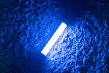 A single blue light stick emits a neon glow, creating a tranquil atmosphere in a dimly lit room...