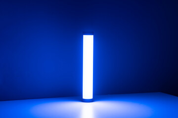 A single blue light stick emits a neon glow, creating a tranquil atmosphere in a dimly lit room...