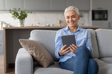 Happy senior woman sitting with digital tablet at living room