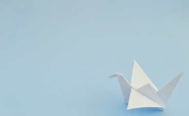 White paper origami bird on blue background. World Day of Peace. Day Against Humiliation....