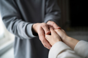 Two people engage in a compassionate touch, offering emotional support through a simple but powerful gesture of connected hands.