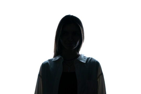 The silhouette of a woman stands enigmatic against a starkly lit white backdrop, her features obscured in shadow, evoking a sense of mystery.