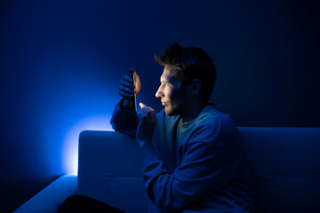 A young person appears to be having an eye problem in a poorly lit room, suggesting the stress of...