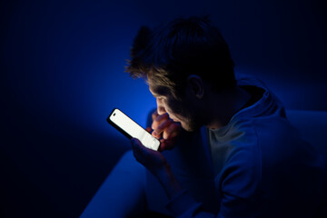 A young person appears to be having an eye problem in a poorly lit room, suggesting the stress of...