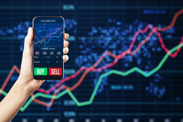 Close up of businesswoman hand holding smartphone with glowing forex chart on dark background....