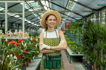 The girl works in the greenhouse, takes care of the plants.