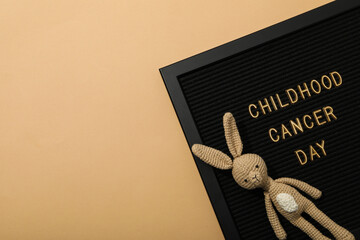 A black board with the inscription Childhood Cancer Day and with a rabbit