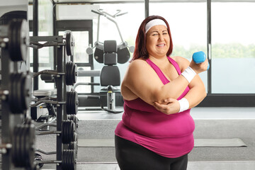 Plus size female exercising at a gym and holding her elbow