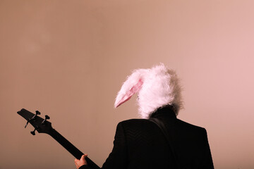 Rock musician wears bunny ears posing with electric guitar. Back view. 