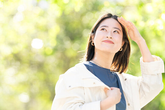 緑バックに上を見上げている女性のビューティーイメージ