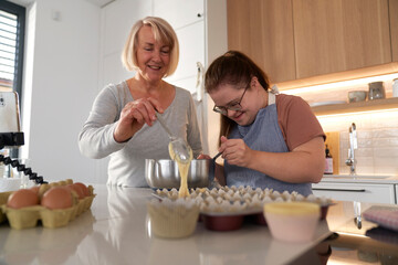 Down syndrome woman and her mother making homemade cupcakes