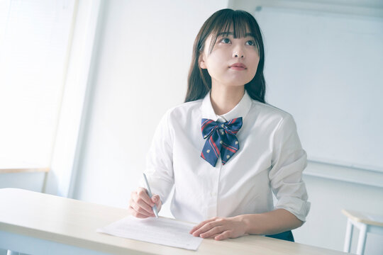 筆記しながら板書を確認している女子校生