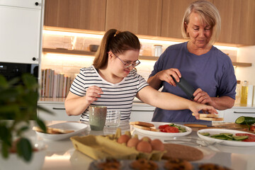 Down syndrome woman and her mother preparing breakfast together