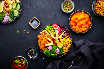 Vegan buddha bowl with sweet potato, quinoa, chickpeas, edamame, tofu, corn, radish, broccoli and...